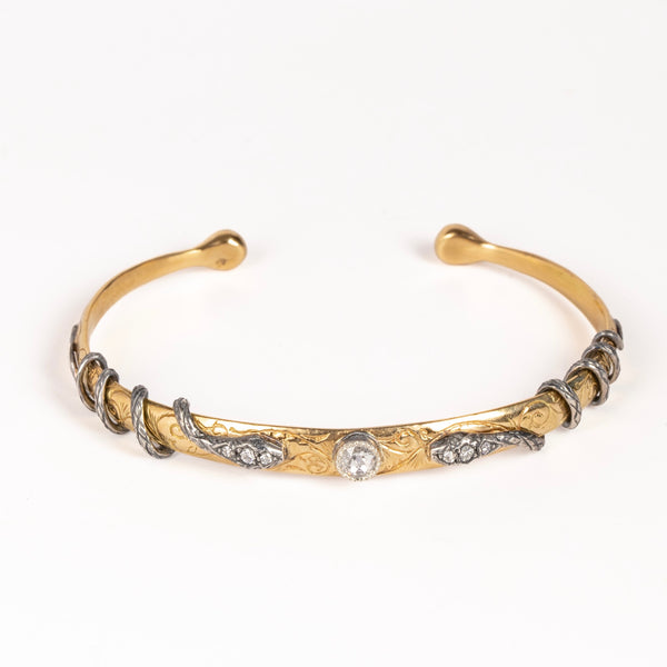 Snake Cuff bravelet by Arman Sarkysian in 18k gold features two coiled snakes  in oxidize d silver with three white diamonds each,l ooking at each other, with a center stoen in the middle on a carved goild cuff that is semi flexible but fits small writst best. 
