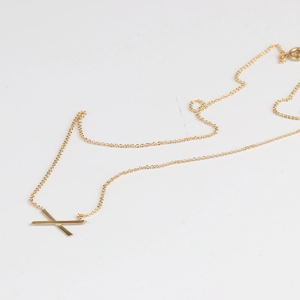 Mini X necklace on white background by Carla Caruso.