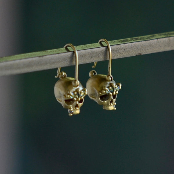 Side view of Green Enchanted Skull Safety Pin Earrings by Polly Wales.