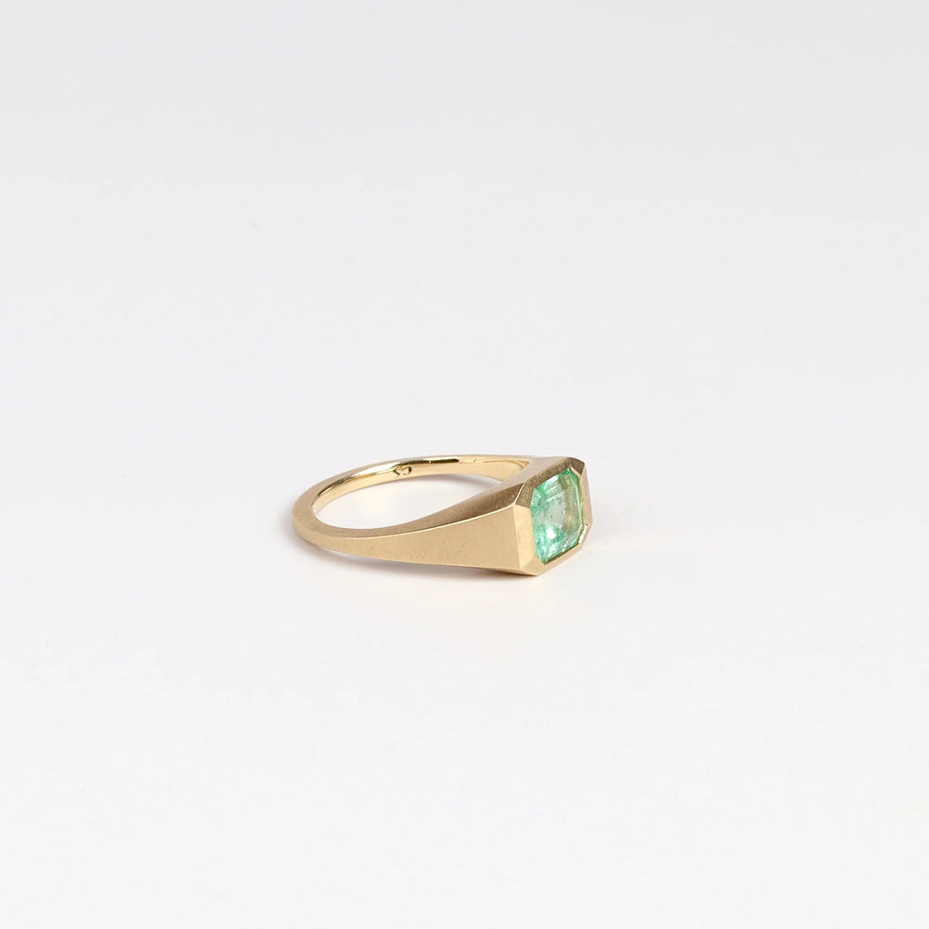 SIde view of Emerald Signet ring by Elizabeth Street Jewelry, a one of a kind lightly faceted Colombian emerald on a tapered band with squared edges in 14k satin finish yellow gold.