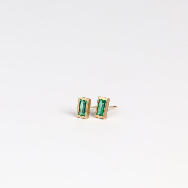 Side view of Elongated Emerald stud earrings with Zambian stone and bezel set in satin finish 14k yellow gold with post closure.
