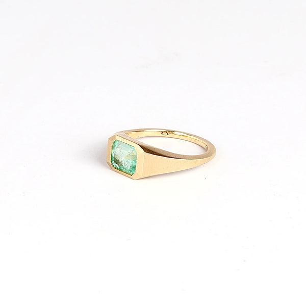 SIde view of Emerald Signet ring by Elizabeth Street Jewelry, a one of a kind lightly faceted Colombian emerald on a tapered band with squared edges in 14k satin finish yellow gold.