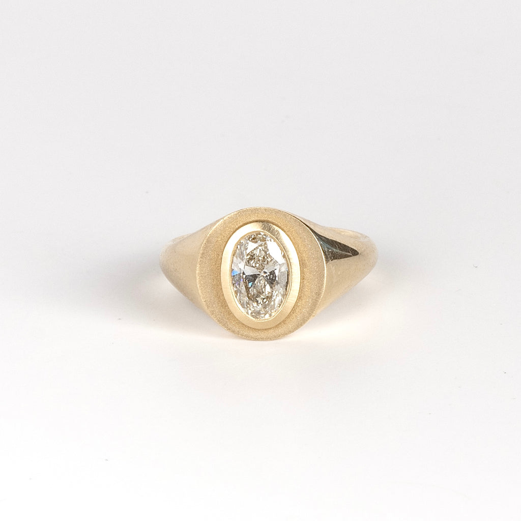 Front of Oval Signet by Elizabeth Street Jewelry. A bezel set oval lab grown diamond in a multi surface circle signet ring on a tapered 14k yellow gold band. Handmade in Los Angeles.