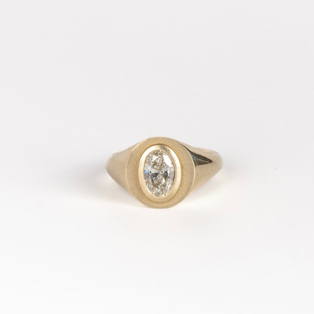 Front of Oval Signet by Elizabeth Street Jewelry. A bezel set oval lab grown diamond in a multi surface circle signet ring on a tapered 14k yellow gold band. Handmade in Los Angeles.