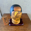 Lifestyle shot of Vintage "Hana Kasumi" is a beautiful Sosaku Kokeshi by master Yoshida Takashi with plaque and stand. 