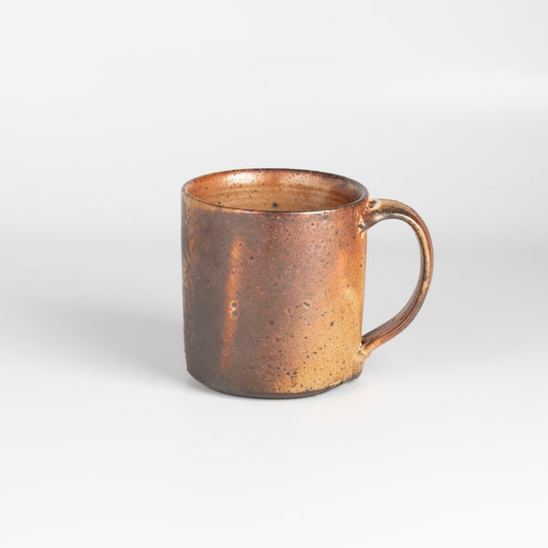 A wood fired  ceramic mug by master of wood fired ceramics, Lindsay Oesterritter. Wood ash in the kiln results in highly varying surfaces so each mug is unique,. As beautiful as they are functional. Sizes vary slightly, glazes considerably. One of a kind.