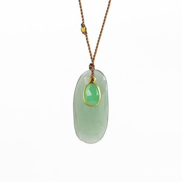 Close up of Chrysoprase and Sapphire necklace, a one of a kind lightly faceted Chrysoprase stone slice accompanied by a smaller green and faceted sapphire slice of which the smaller is set in 18k gold with with a gold bead on the string makes this one of a kind &nbsp;organic pendant necklace. Designed by Margaret Solow. Handcrafted in Los Angeles.