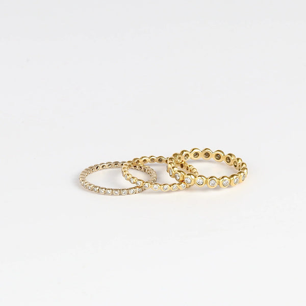 1mm, 1.25mm and 3mm thick diamond porch bands by Marian Maurer on white background. These wedding bands are made out of bezel set round diamonds.