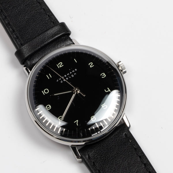The Max Bill 34mm Hand wound wrist watch with black dial face and numbers, but no date was designed for Junghans in 1961 and is virtually unchanged. It is a classic modernist design with hand winding movement J805.1 (ETA 2801-2) and a sapphire crystal,  42 Hour Power Reserve in 316L stainless steel case available at OK