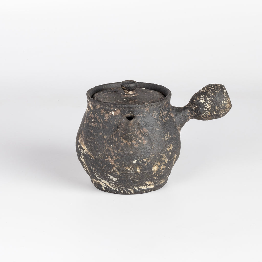 Kyusu teapot B by Muzuri Ware is a composed ceramic teapot, utilizing mostly black stained London clay, textured and inlayed with costal wild Cornish clay. This one is inlayed with black iron oxide. Wheel thrown and assembled with interior holes to work with a variety of tea leaves by Kyriacos Mouzouris in London UK.