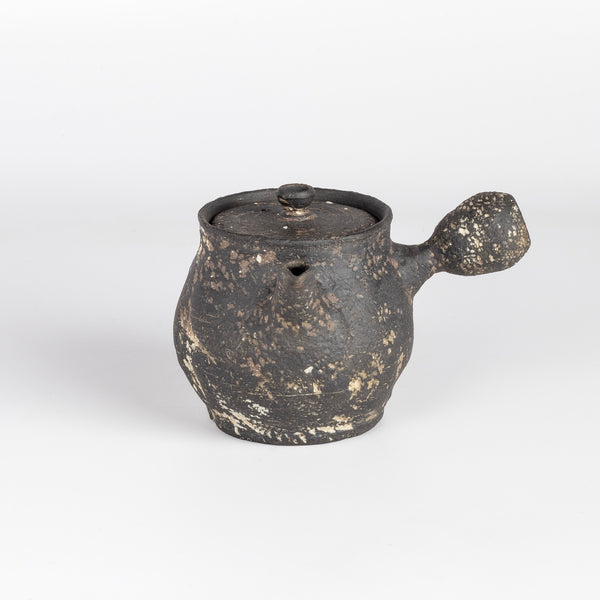 Kyusu teapot B by Muzuri Ware is a composed ceramic teapot, utilizing mostly black stained London clay, textured and inlayed with costal wild Cornish clay. This one is inlayed with black iron oxide. Wheel thrown and assembled with interior holes to work with a variety of tea leaves by Kyriacos Mouzouris in London UK.
