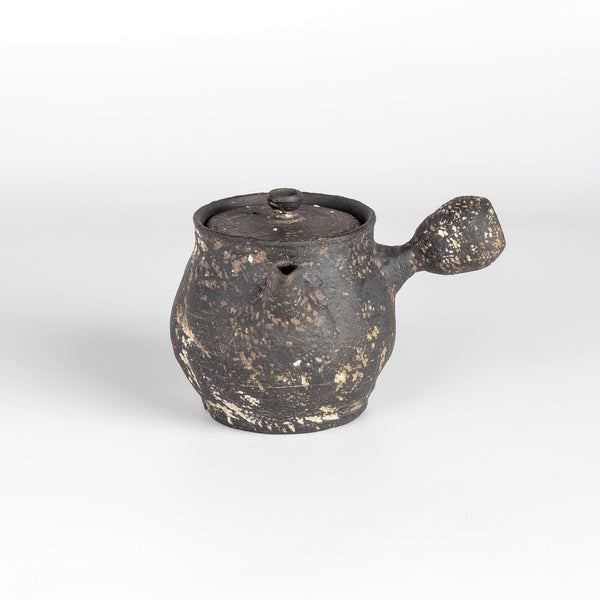 Kyusu teapot B by Muzuri Ware is a composed ceramic teapot, utilizing mostly black stained London clay, textured and inlayed with costal wild Cornish clay. This one is inlayed with black iron oxide. Wheel thrown and assembled with interior holes to work with a variety of tea leaves by Kyriacos Mouzouris in London UK.