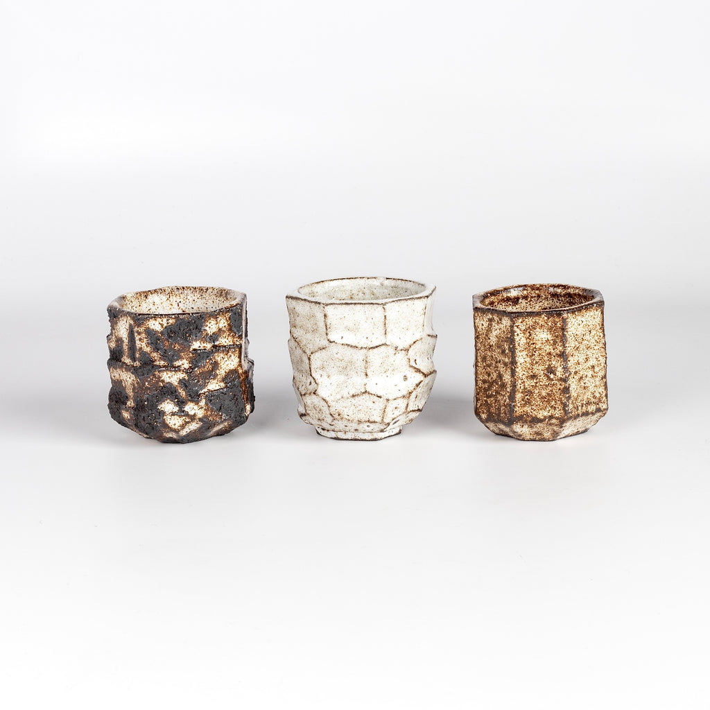 Kurinuki Yunomi Teacups are hand carved tea cups from a single block of black stained clay with varying grog (fired ceramic aggregate) and finished with a tin white glaze. Food safe. Made by Kyriacos Mouzouris in London UK.