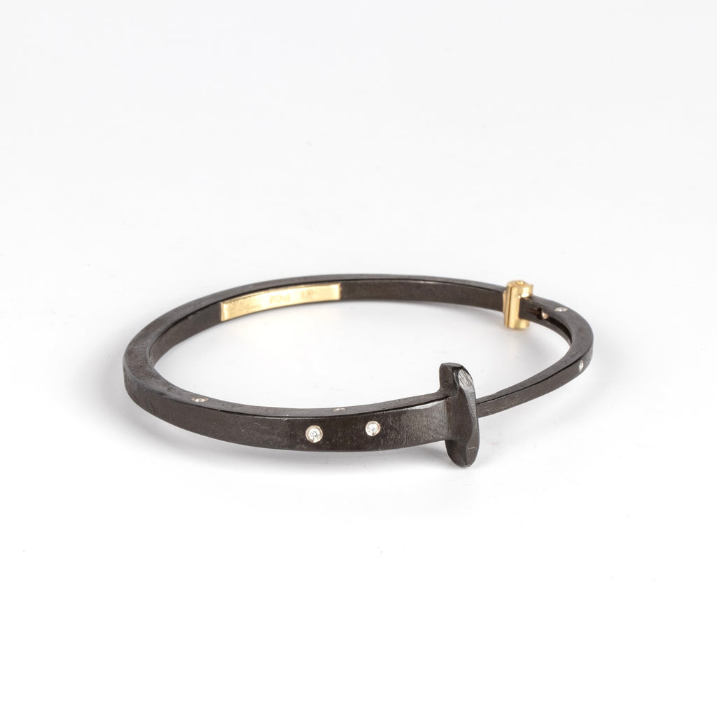 A Forged nail bracelet with nine scattered accent diamonds and completed with an 18k gold hinge and ball catch closure by Pat Flynn. 