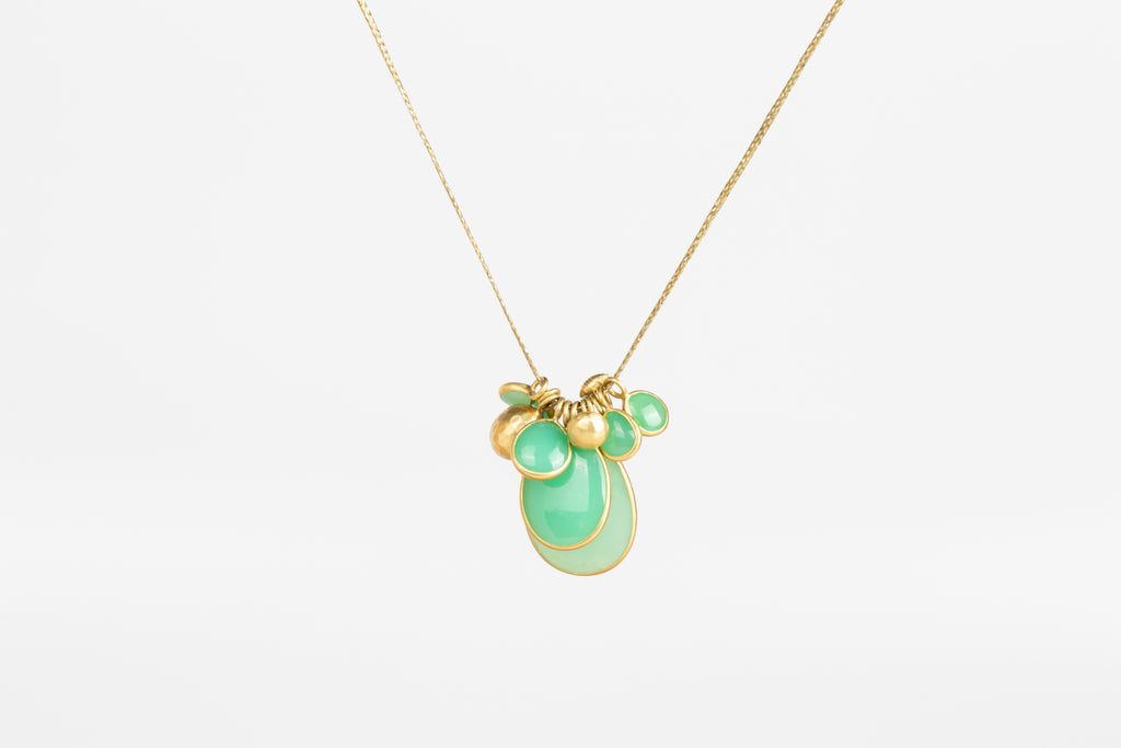 Colette Chrysoprase Cluster Necklace in Flourishing Greens is a necklace by Pippa Small Jewelry in the Flourishing Greens color way is a cluster of bezel set Chrysoprase stones in various sizes with two hammered 18k gold seed beads and one mini croissant bead on a 22" golden waxed cotton cord.