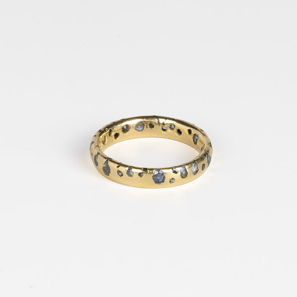 The Cornflower Blue Sapphire Confetti Band designed by Polly Wales is a narrow 18k yellow recycled gold wedding band/ring with speckled ombre light blue sapphires around the circumference. It is cast not set and handmade in Los Angeles.