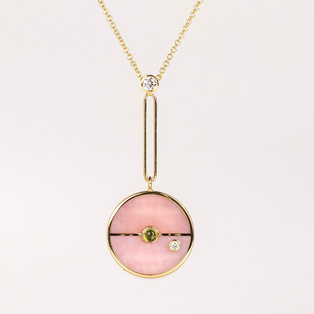 Compass Pendant in Pink Opal and Green Tourmaline by Retrouvai is a unique modern take on an heirloom pendant. Stone inlay is accented with a center gem stone and white diamond. The compass hangs from an elongated paperclip link accented with a second white diamond. Handcrafted in Los Angeles.