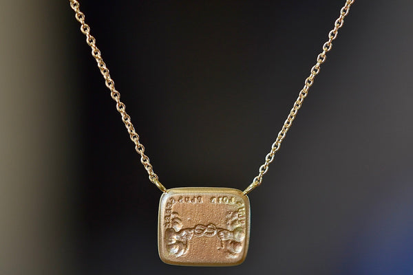 Love Knot duo moto necklace by Makiko Wakita in close up with words: “Plus Loin Plus Serré” which translates to ‘the further apart the tighter the bond.’ Far apart, close at heart.