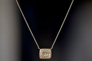 Lion and Mouse Duo Motto Necklace in 18k gold is a rectangular disc in gold with satin finish that will turn shiny over time features an image from the Aesop Fable ‘The Lion and the Mouse featuring the words 'patience". Made by stamping an 1800s carved seal with 'mottos' in French, Italian, Latin or English on to gold. 