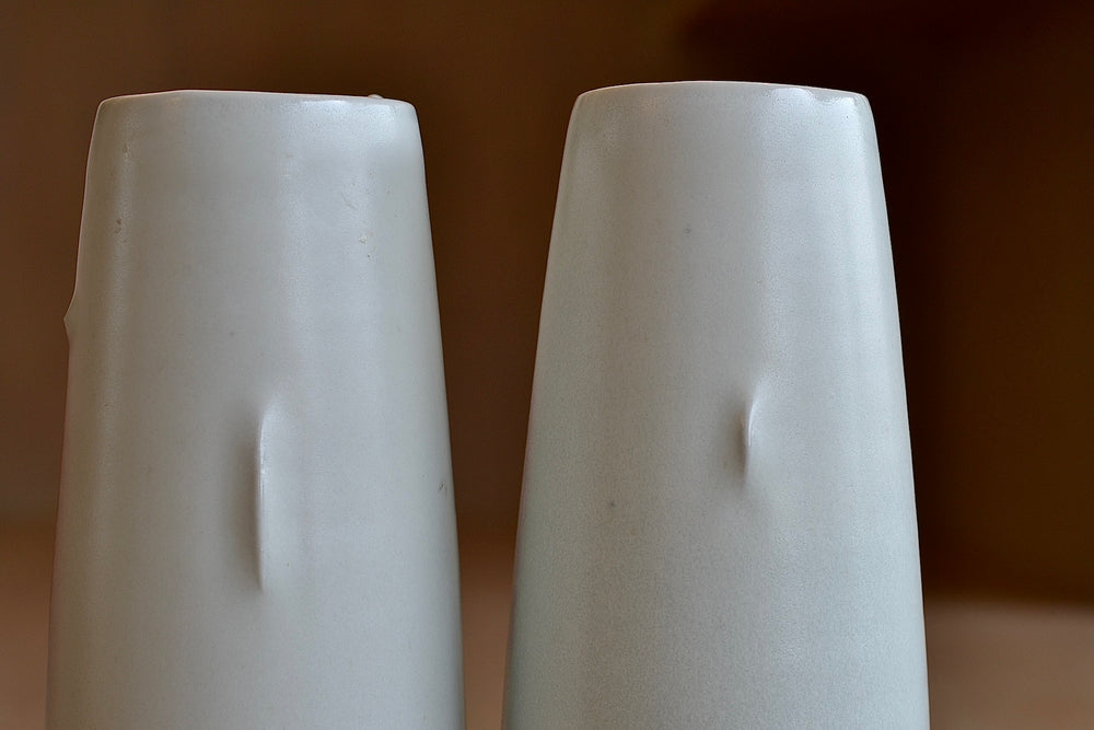 Long and short crease pinched vases by Hyesjeong Kim next to each other.