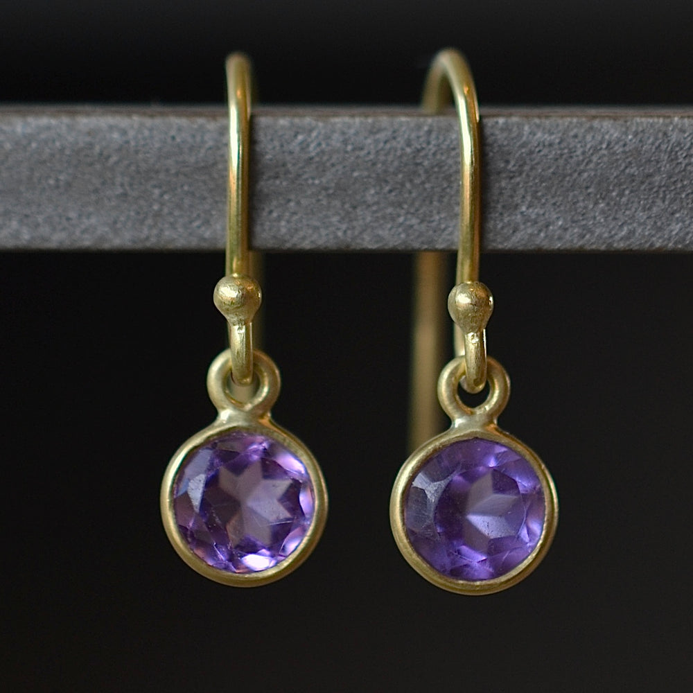 Tiny moon earrings by Tej Kothari are lightly faceted and translucent bezel set round and inverted stones on a gold ear wire hook in amethyst.