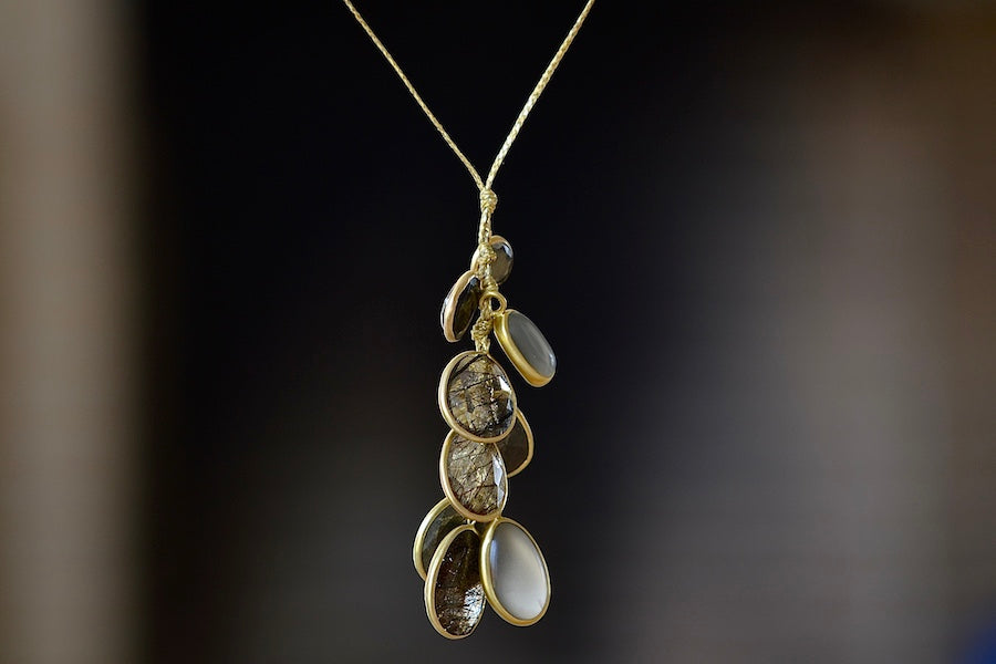 
            
                Load image into Gallery viewer, The Colette Set Cluster with Pyrite, Hematite, Tourmalated Quartz and Gray Moonstone Pendant Necklace is a cluster of nine bezel set, smooth or lightly faceted stones including Pyrite, Hematite, Tourmalated Quartz, and Gray Moonstone, all in 18k yellow gold on a 23&amp;quot; golden waxed cotton cord form this necklace. 
            
        