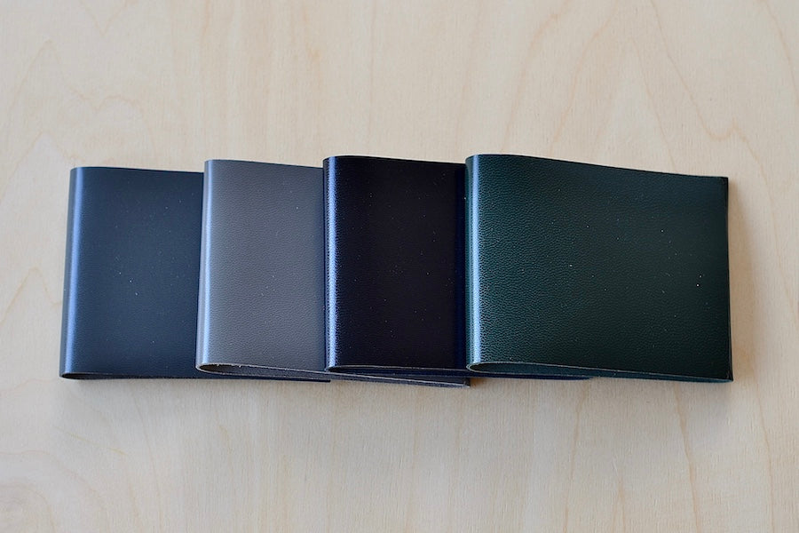 Simple Flap wallets in dark and soft gray, black and dark green from architect Alice Park shown folded.