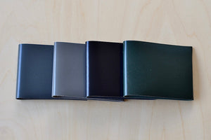 Simple Flap wallets in dark and soft gray, black and dark green from architect Alice Park shown folded.