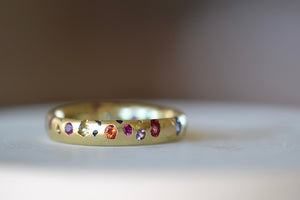 Polly Wales Classic Rainbow Confetti Band Ring in 18k recycled yellow gold with green, yellow, orange, blue, purple and pink sapphires and cast not set. Size 7.
