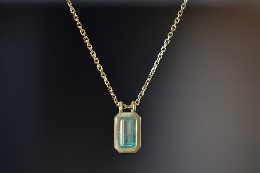 The Duo Bale Emerald Pendant Necklace by Elizabeth Street Jewelry Katie Finn is a bezel set rectangular and translucent shaped Columbian emerald on a double bale and on a 18k yellow gold chain. Perfect for layering or to wear as a solo piece. Handmade in Los Angeles.
