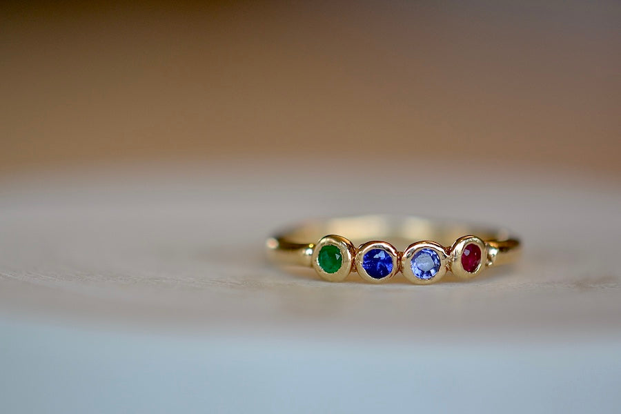 Rise ring by Makiko Wakita is a A message ring with four bezel set gem stones. One roundish Ruby, one Iolite, one Sapphire and one Emerald spell out RISE and are attached to an organically shaped narrow gold band to be worn on any finger. Handmade in Los Angeles.