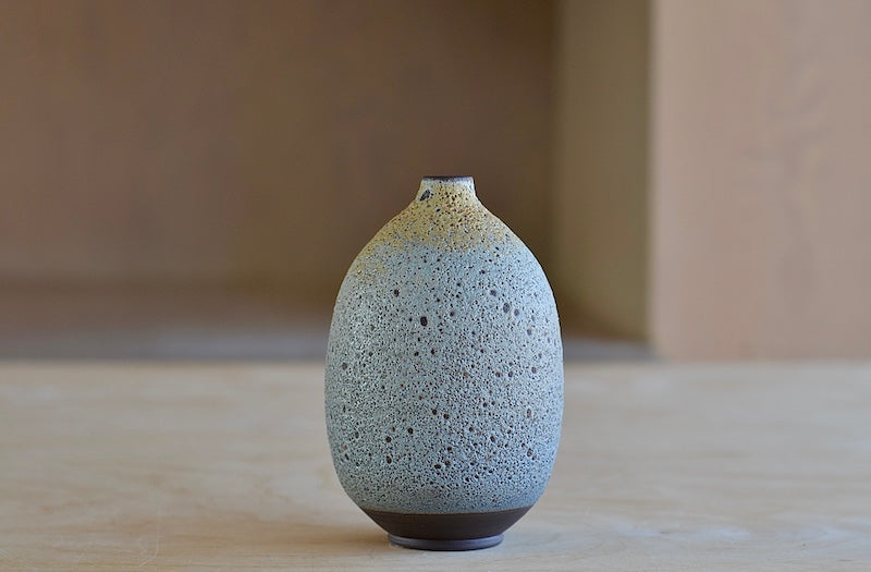 Heather Rosenmann Blue and Yellow Volcanic Bottle Vase is a A Hand thrown stoneware vase with volcanic glaze in blue to yellow available at OK. Each vase is hand-thrown, unique and stamped by the artist herself. 