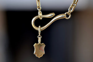 
            
                Load image into Gallery viewer, Meredith Kahn small shiny shield Charm with loop ring in brass or solid 14k yellow gold on a hook and loop cable chain necklace..
            
        