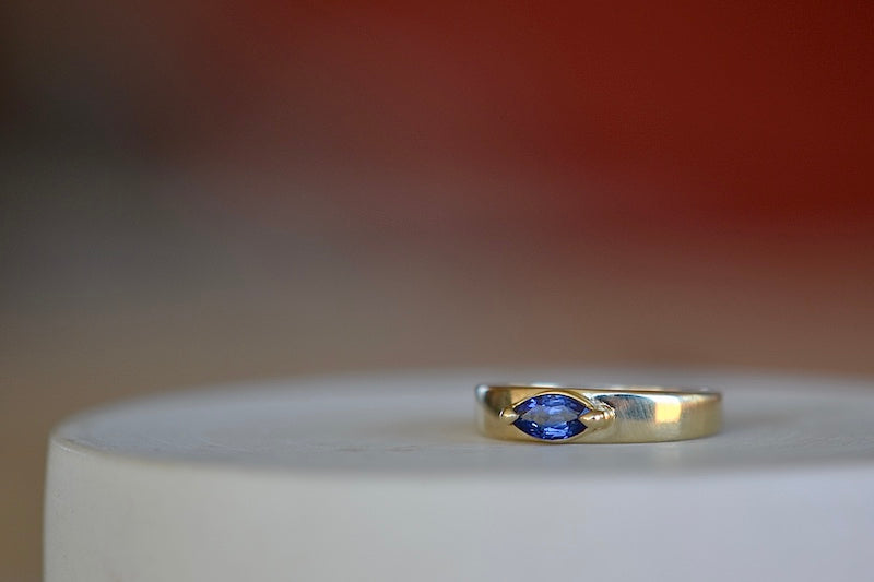 
            
                Load image into Gallery viewer, Stoned Slim Cigar Band in Blue Sapphire size 6.5 by Elizabeth street is a marquise cut sapphire in a two prong eagle claw bezel setting on a 14k yellow gold band. .
            
        