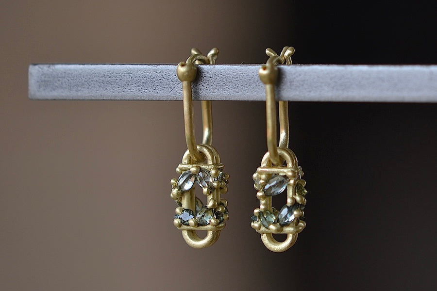 
            
                Load image into Gallery viewer, The Short Fontaine Bar Earrings in Green by Polly Wales from the side are A hinge lock hoop in 18k gold is attached to a rectangular box that has an encrusted vine of inverted green to gray mixed sapphires with matte gold dots.
            
        
