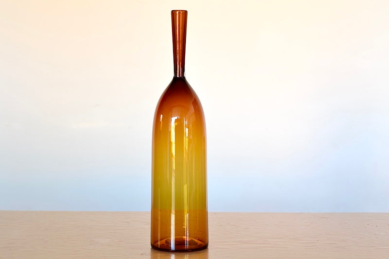 Angelic Bottles by Joe Cariati are mouth blown  Freeblown by glass master Joe Cariati in his Southern California studio, these bottle-form vases evoke the more mass produced mid-century ones that inspired them, small amber orange.