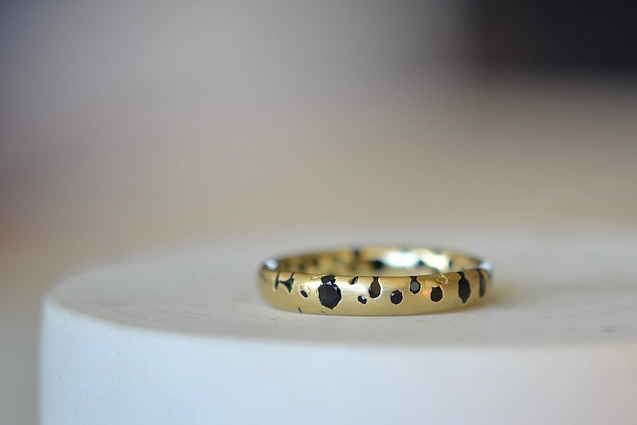 The Black Sapphire Confetti Band in size 8 designed by Polly Wales is a narrow 18k gold wedding band/ring speckled with black sapphires around the circumference. Cast not set. Made in Los Angeles. 