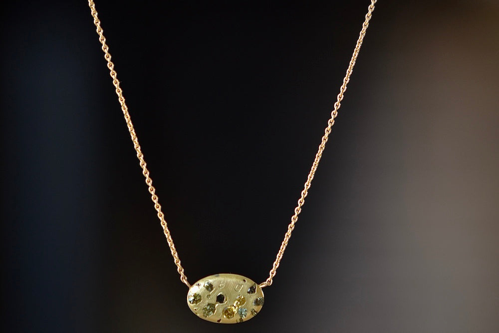 Elysian Necklace by Polly Wales is An oval disc in 18K yellow gold with scattered confetti style rainbow sapphires in yellow, green and black on a beautiful 18k yellow gold chain 18".  Recycled gold. Cast in Place. Cast not set. Handmade in Los Angeles.
