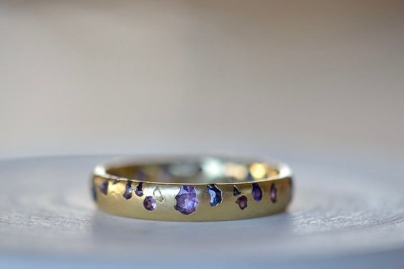 
            
                Load image into Gallery viewer, The Purple and Blue Sapphire Band Ring by Polly Wales is a narrow 18k yellow gold band with speckled purple, pink, blue to navy and black sapphires around the circumference for a beautiful confetti-like appearance. Recycled gold. Cast not set.
            
        