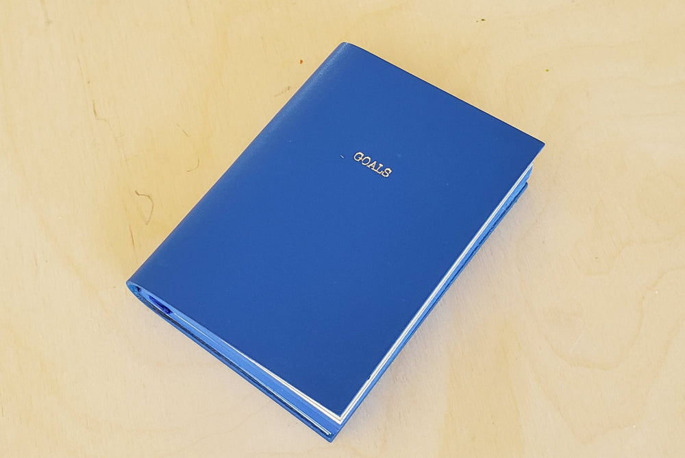 
            
                Load image into Gallery viewer, Leather Raw Edge Small Journal in blue with Goals printed on the front.
            
        