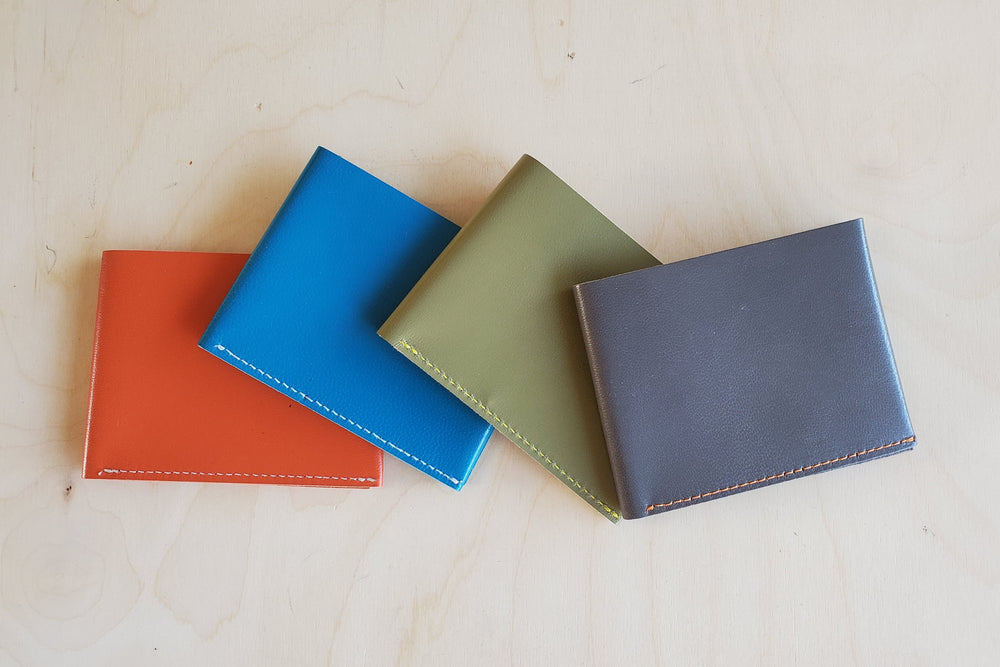 
            
                Load image into Gallery viewer, Simple Flap wallets in orange, blue, grey and olive green leather and white stitching from architect Alice Park shown folded.
            
        