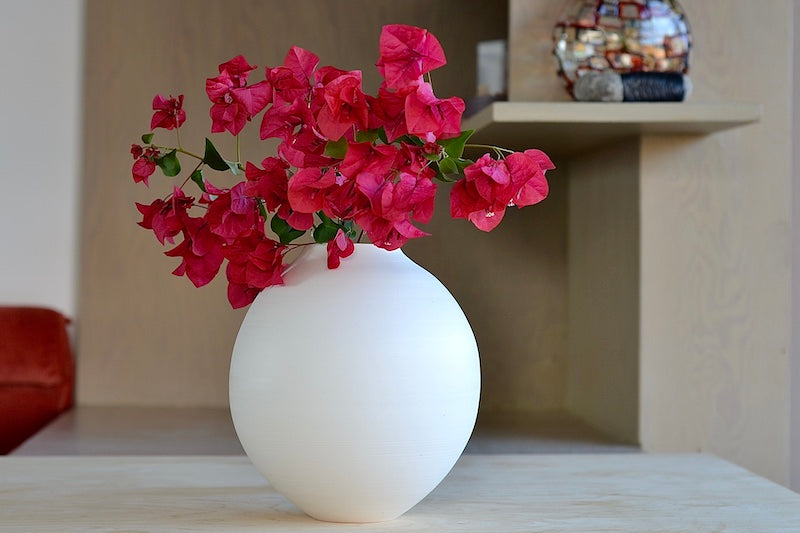 
            
                Load image into Gallery viewer, Lilith Rockett Large Round Vase is wheel thrown porcelain with gloss glaze on the interior and an unglazed exterior. Shown with flowers.
            
        