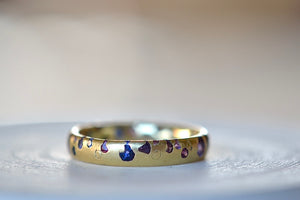 
            
                Load image into Gallery viewer, Alternate view of the Purple and Blue Sapphire Band Ring by Polly Wales is a narrow 18k yellow gold band with speckled purple, pink, blue to navy and black sapphires around the circumference for a beautiful confetti-like appearance. Recycled gold. Cast not set.
            
        