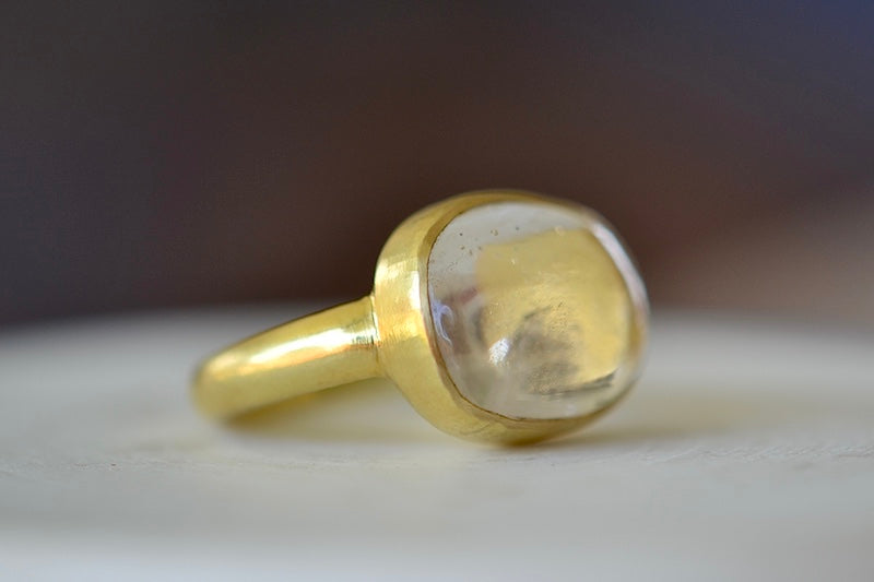 The Crystal Large Greek ring by Pippa Small is an Organically shaped mostly clear and transparent to translucent crystal with natural inclusions set in 18k yellow gold (side view).. 
