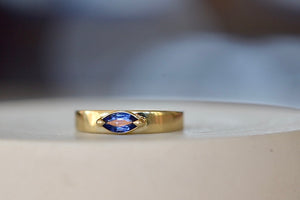 Stoned Slim Cigar Band in Blue Sapphire size 6.5 by Elizabeth street is a marquise cut sapphire in a two prong eagle claw bezel setting on a 14k yellow gold band.