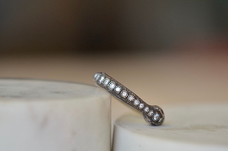 The Ouroboros Band by Arman Sarkyssian is a ring depicting a snake, swallowing its tail in oxidized silver with a half eternity diamond setting on its back. Eternity diamond setting detail.