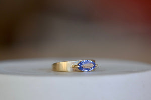 Stoned Slim Cigar Band in blue  Sapphire size 6.5 by Elizabeth street is a marquise cut sapphire in a two prong eagle claw bezel setting on a 14k yellow gold band.