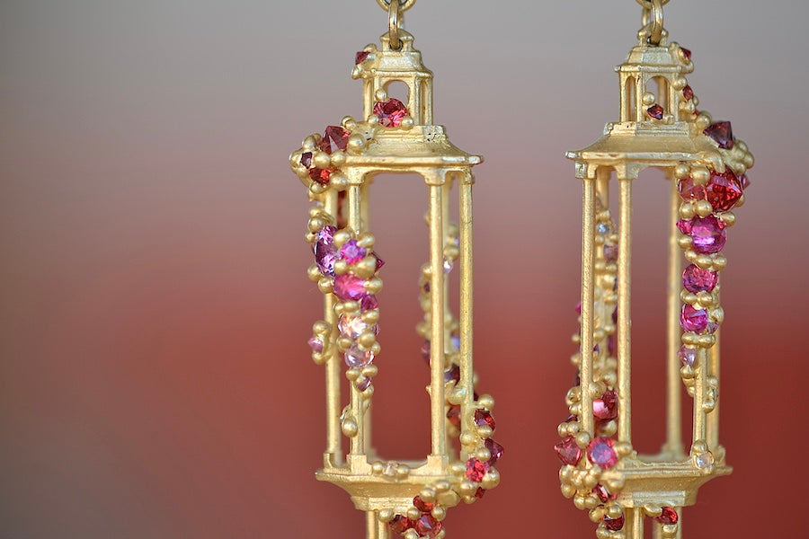 Polly Wales Jade Terrace Pagoda Earrings 18K yellow recycled gold pagoda forms hanging from a bird stud encrusted with a pearl pink and orange sapphire sapphires. Cast not set.