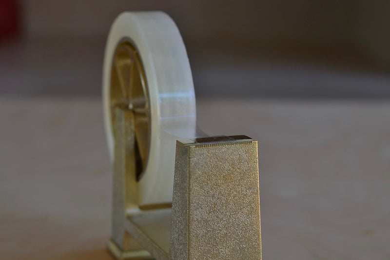 Futagami Large Brass Tape Dispenser is A handmade brass tape dispenser in Ihada finish with a larger wheel for tape with an inner diameter of 3" from a foundry founded in 1897 in Japan's Toyama prefecture. Designed by Masanori Oji to easily be moved with one hand. Heritage.