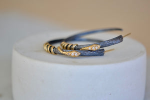 
            
                Load image into Gallery viewer, The Snake Hoop Earrings by Arman Sarkyssian on a stand..
            
        